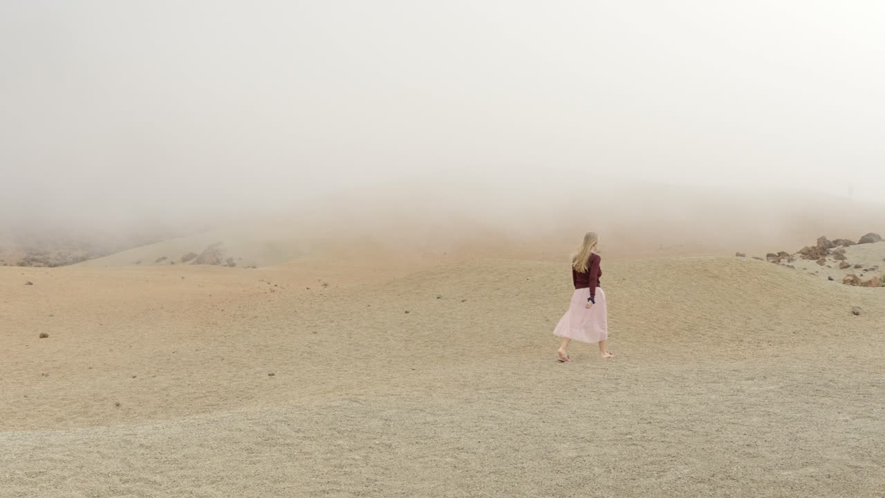 mujer caminando en el parque nacional del teide en un día de niebla, fuera de esta escena mundial
