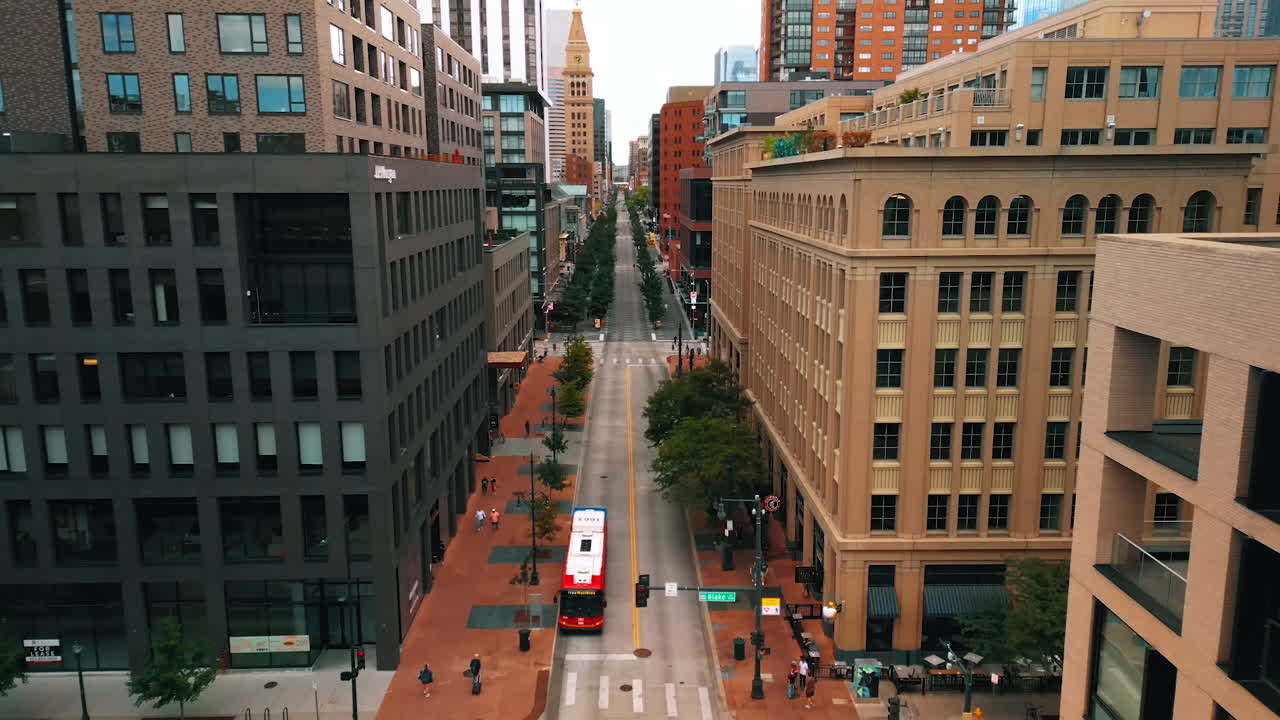 Denver, USA, 28 July 2025: Street of Denver, Colorado, USA lined up by the green trees and beautiful modern buildings. Few people walk or ride by the sidewalks