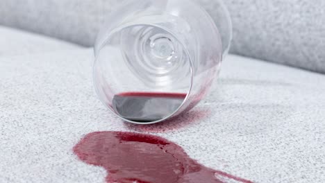 camera hovers above couch, peering into tipped glass and dark stain
