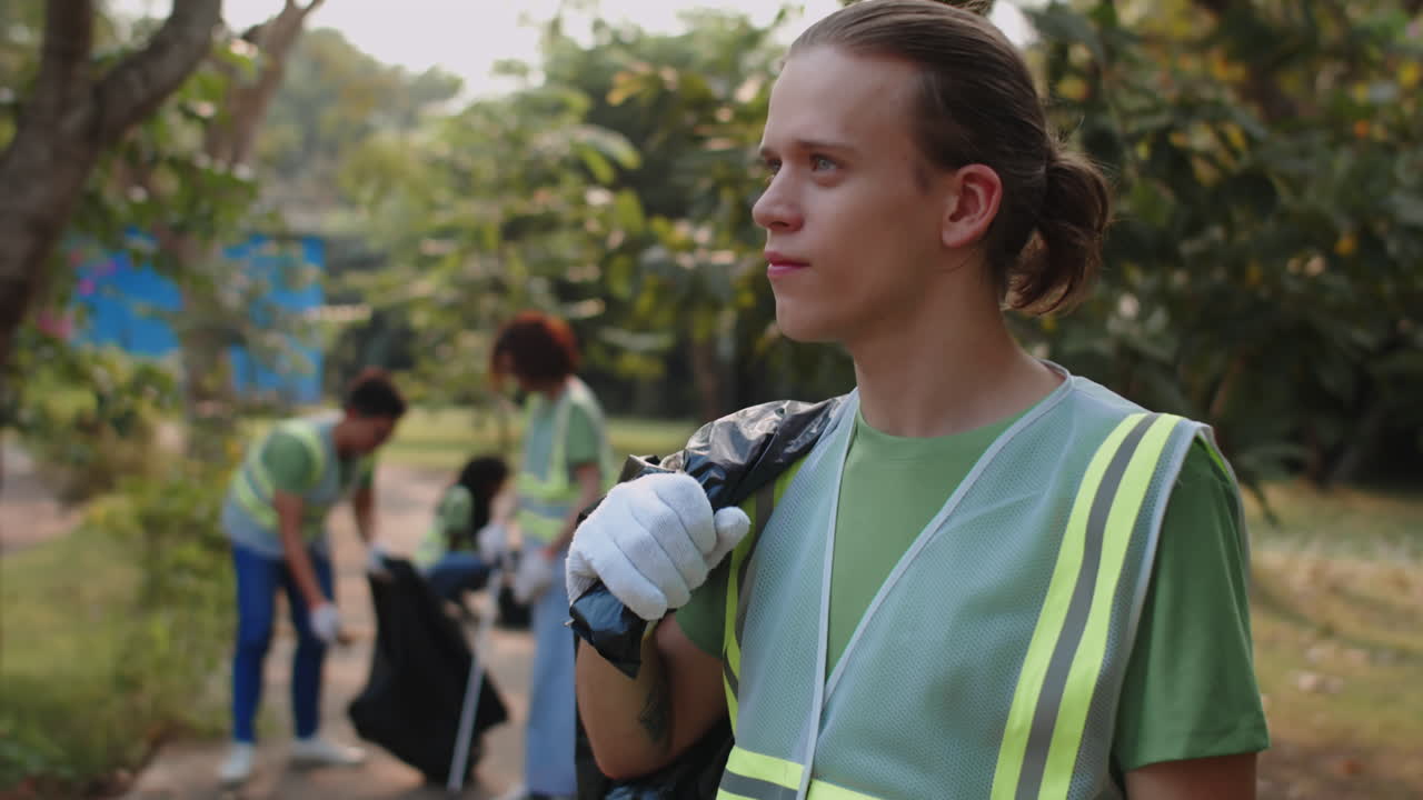 Male Caucasian Volunteer Holding Bag with Collected Garbage Outdoors