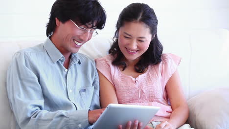 couple smiling as they use a tablet computer