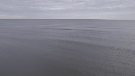 drone flying over ocean - 4k beach shot on overcast day