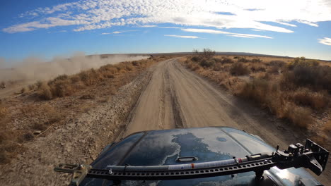 carreras pov en un paisaje desértico detrás del rastro de polvo de un vehículo más rápido