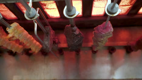 skewers of meat cook in a churrasco rotisserie grill, brazilian steakhouse kitchen, slide slow motion hd