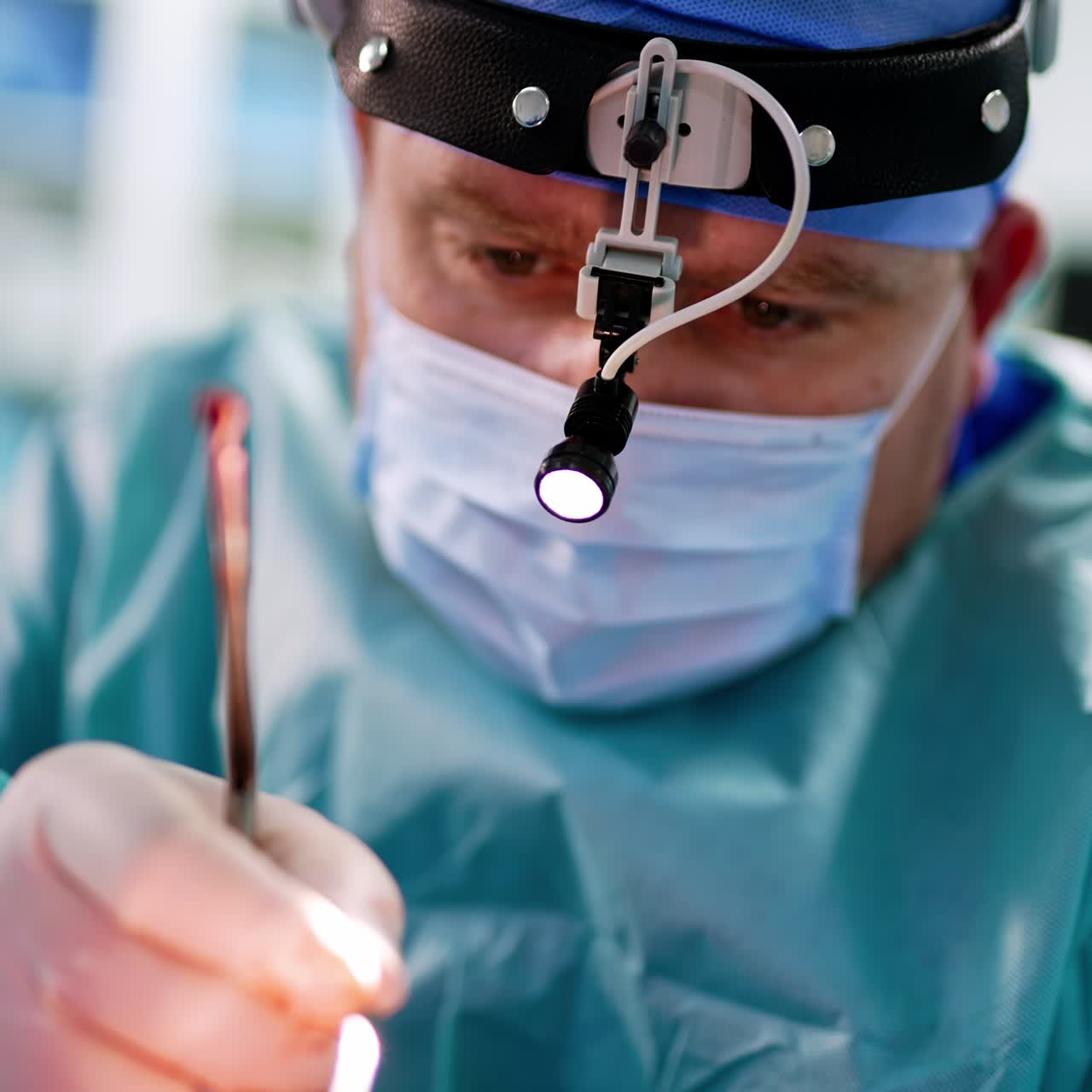 Concentrated face of a male surgeon being busy at operation. Close up portrait of a doctor performing nasal surgery