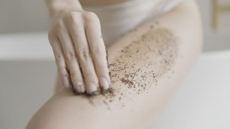 mujer aplicando exfoliante de café a la pierna