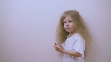 girl with blond loose hair dances posing on white background