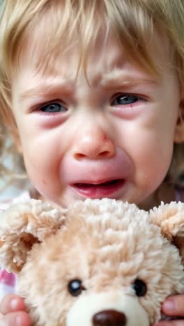a blonde little boy crying hugging his teddy bear
