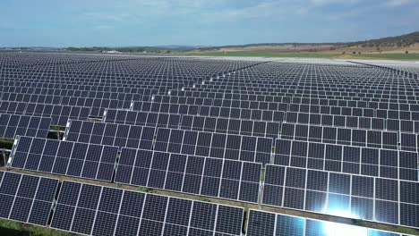 Drone-shot-of-Solar-Farm,-flying-over-field-of-solar-panels,-rotational-shot,-with-sun-flare-and-reflections-within-the-panels,-shot-at-in-afternoon,-in-Warwick-Queensland-Australia-4K