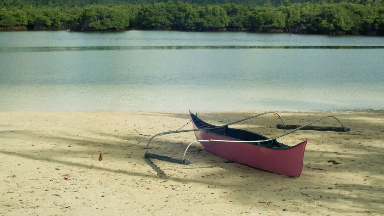 Pink boat docked on white sand of Secret Beach Malinao in Siargao.