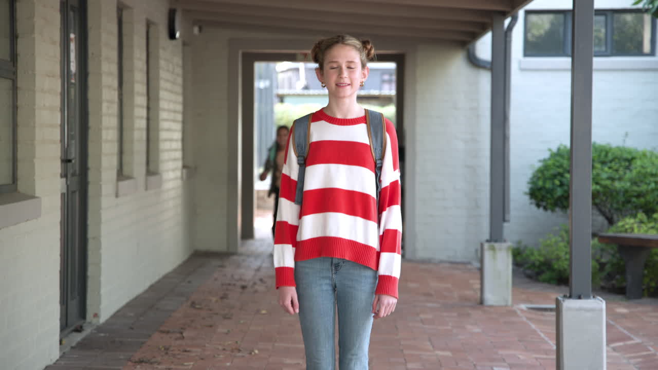 Smiling girl with backpack enjoying school day in outdoor corridor, copy space