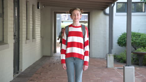 smiling girl with backpack enjoying school day in outdoor corridor, copy space