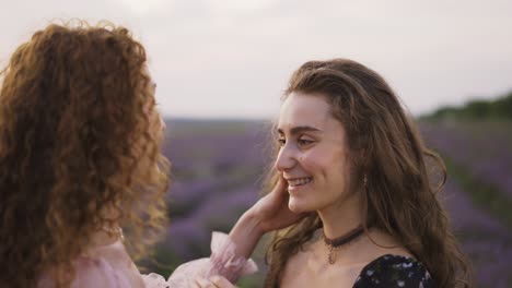 two sensual women among a lavender field, funny rubbing their noses