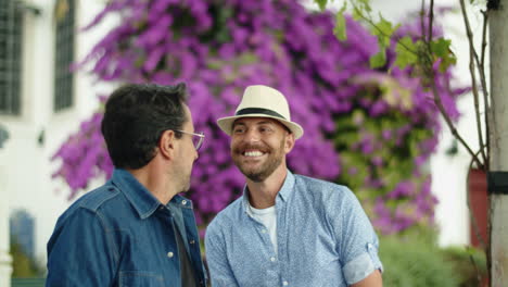 cámara lenta de un hombre gay con sombrero coqueteando con su novio sonriente