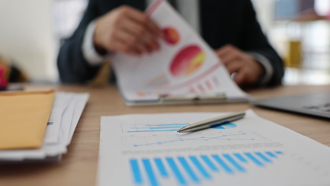 Businessman studies documents with diagrams sitting at table