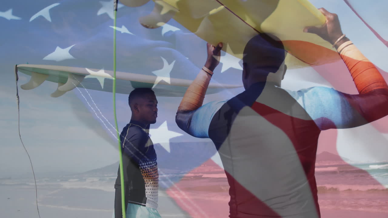 Carrying surfboards with American flag overlay, surfers walking on beach sand