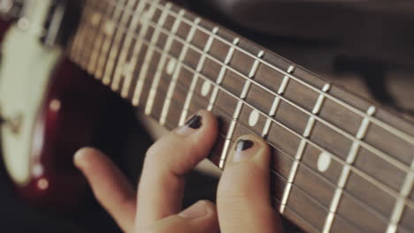 hands with a shabby black nail polish playing the guitar