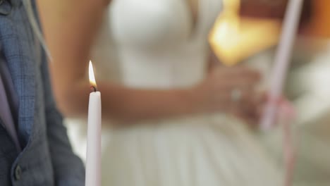 the bride and the groom stand in church, holding candles in their hands