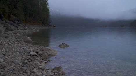 calm lake eibsee transparent water with low clouds across zugspitze mountain at daybreak