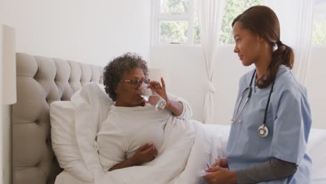 mixed race woman being visited at home by a nurse. social distancing and self isolation in quarantin