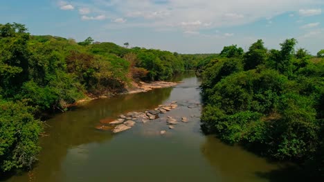 Drone-flying-in-low-over-a-river-flowing-through-the-countryside