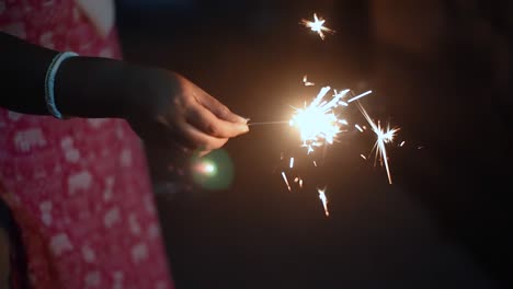 chica irreconocible sosteniendo galleta de fuego por la noche, primer plano, cámara lenta