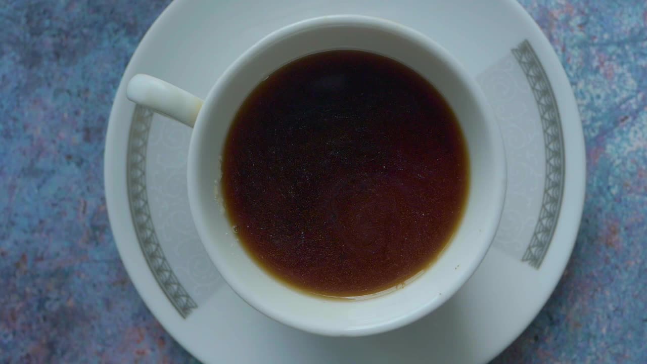 una persona mezclando azúcar en una taza de café