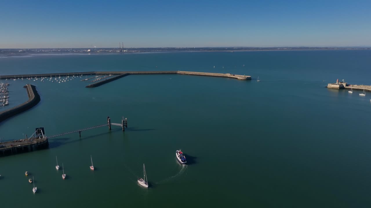 Dublin Bay Cruises Boat, Dún Laoghaire, County Dublin, Ireland, September 2024. Drone panoramic high angle clockwise orbit above the historic Harbour with Howth and Dublin Bay in the background