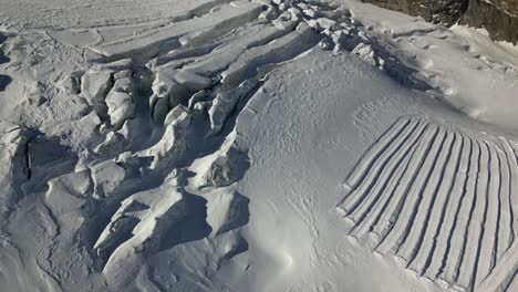 aerial-tilt-up,-snow-covered-surface-in-the-swiss-alps-in-winter,-cold-weather