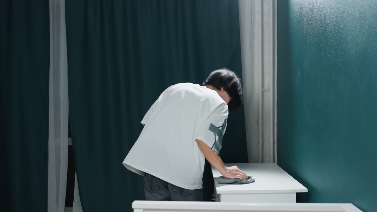 스프레이와 천을 사용하여 가정용 캐비닛을 체계적으로 청소합니다. 부지런한 젊은이가 스프레이와 극세사 천으로 가정용 캐비닛 표면에 대한 상세한 소독 루틴을 수행합니다.