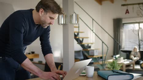 handome inspired man typing on laptop while standing at table at home