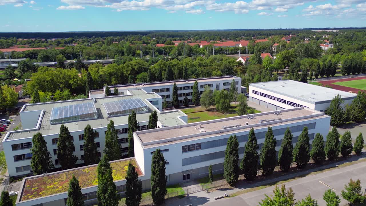 Hennigsdorf High School showcasing its modern architecture, sports facilities, parking area, surrounding urban landscape. Wonderful aerial view speed ramp hyper motion time lapse ascending drone