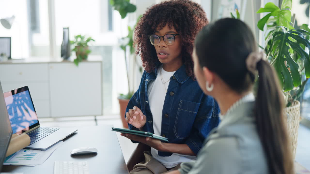Two Diverse Businesswomen Collaborating and Discussing Work in a Modern Office
