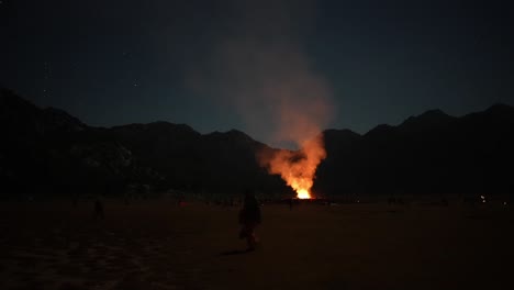 night scene with big campfire and people wondering, stars night sky camping