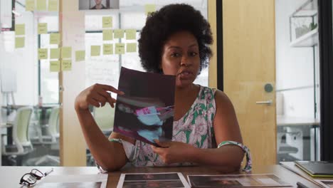 Smiling-african-american-businesswoman-at-desk-talking,-showing-image-during-video-call-in-office