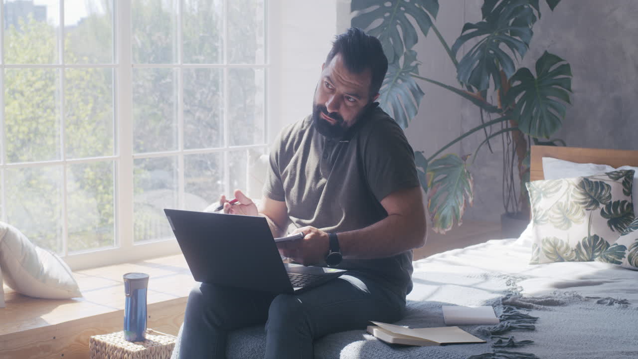 Man Working on Laptop in a Bedroom