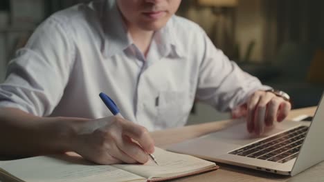 person working on laptop and notebook at night