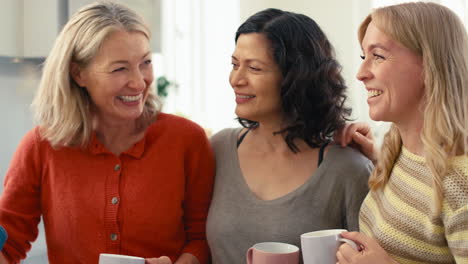 multi-generation female family with same sex partner sitting in kitchen at home talking