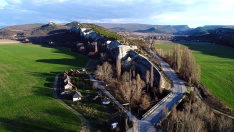 aerial view of a valley with a road, mountains, and houses