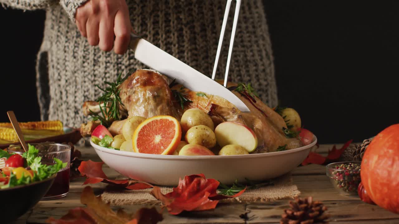 video de la sección media de una mujer caucásica cortando pavo asado en la mesa con decoración de otoño