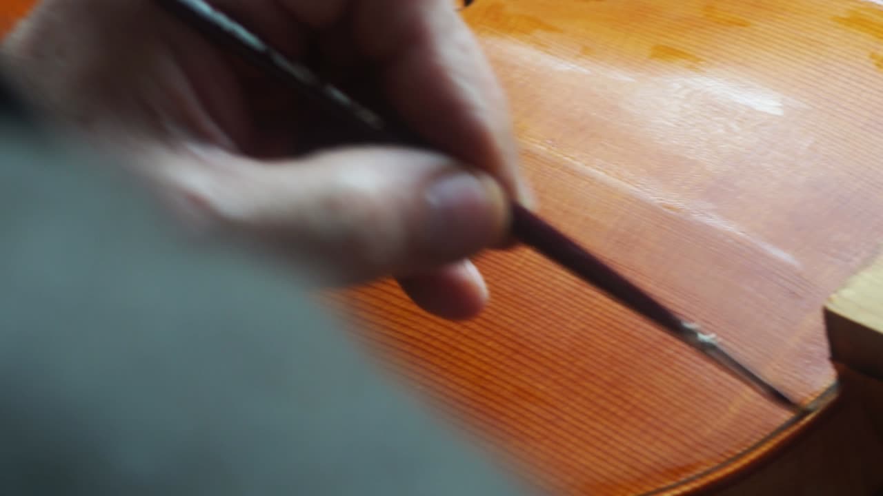 mano de un luthier fabricante de violines barnizando un instrumento de cuerda de madera hecho a mano