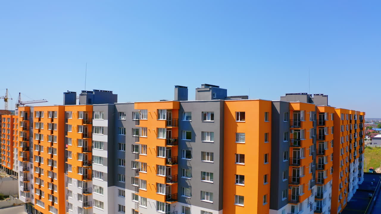 Bright multi-storey building in sunny day. Modern design of high-rise apartment building in the city. Exterior of new block of flats for residents under blue sky.