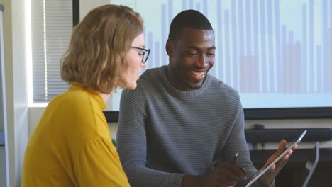 Junge-Geschäftskollegen-Mit-Gemischter-Abstammung-Diskutieren-über-Ein-Digitales-Tablet-In-Einem-Modernen-Büro-In-4K