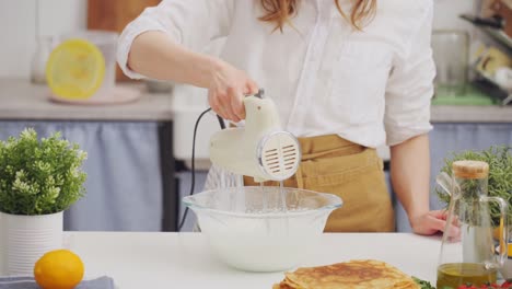 anonymous woman chef using a mixer whipping a batter