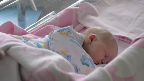 mother covering sleeping baby with blanket