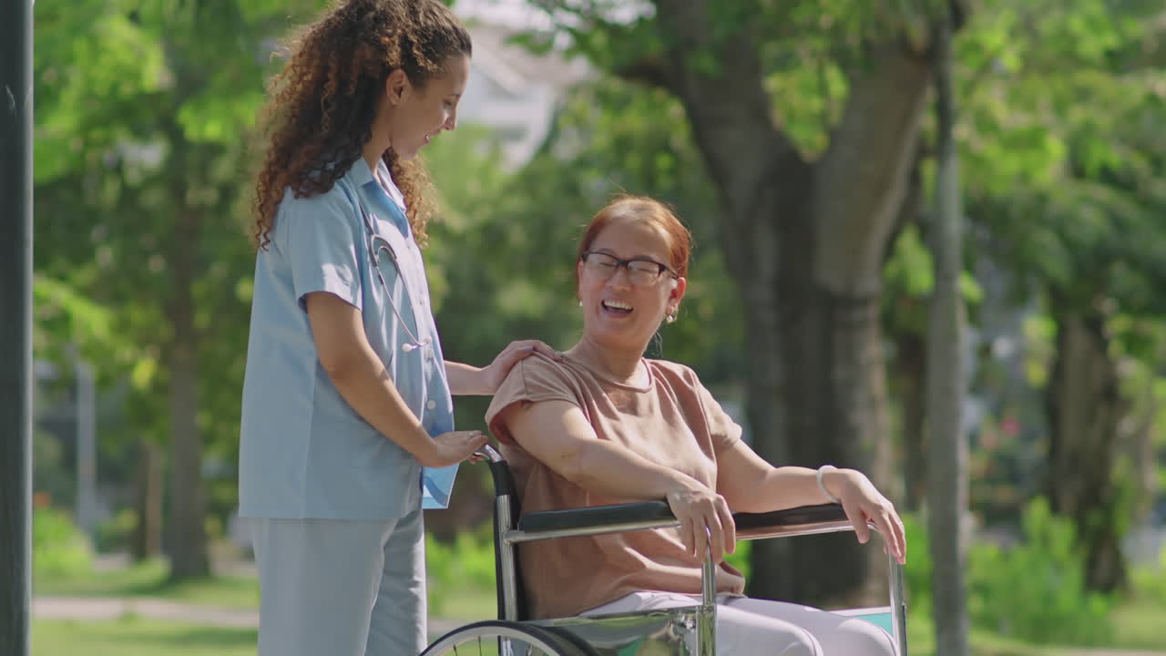 Nurse assisting elderly woman in wheelchair at the park