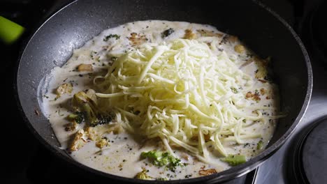 adding mozzarella cheese and flour to pasta sauce cooking in a skillet