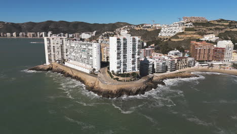 twin high-rises facing the sea as waves roll onto platja de l'illa at midday