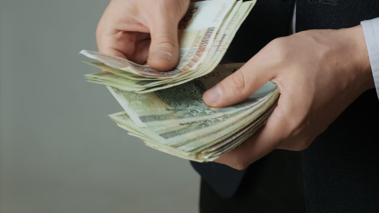 남자의 손은 신속하게 지폐를 계산합니다. 사업가는 손에 폴란드 슬로티의 지폐를 셀 수 있습니다.