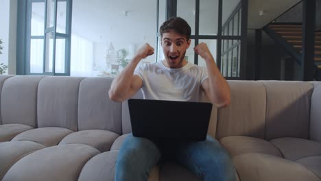 hombre de negocios feliz haciendo un gesto de sí cerca de la computadora portátil en un lugar de trabajo remoto.